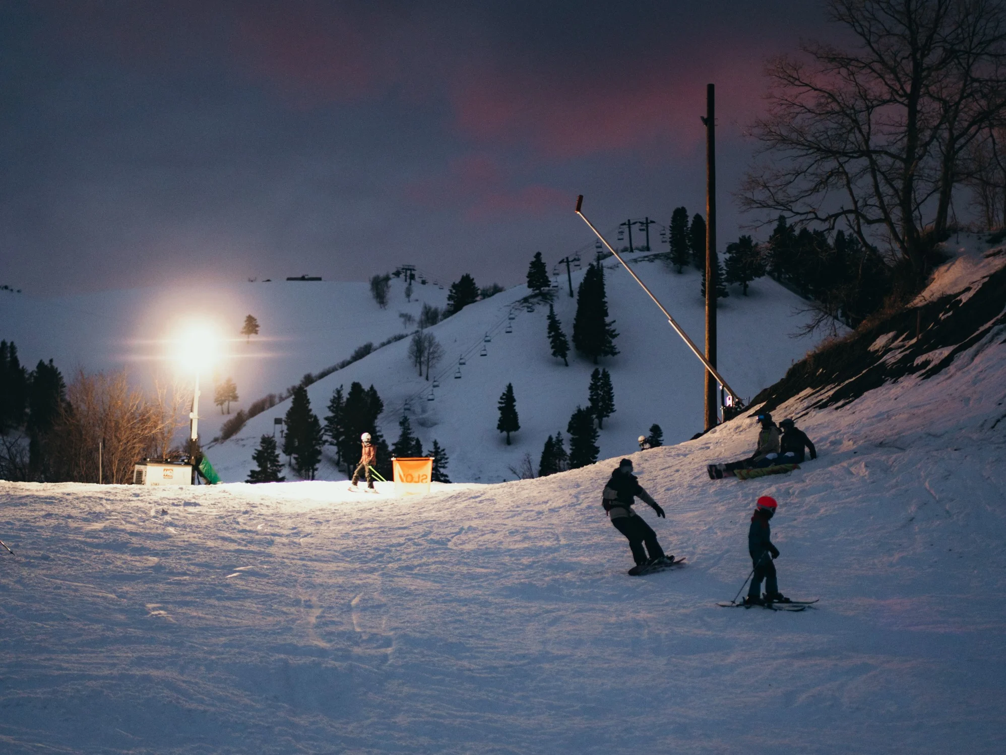 Evening view of the mountainside with people out on the slopes for night skiing.